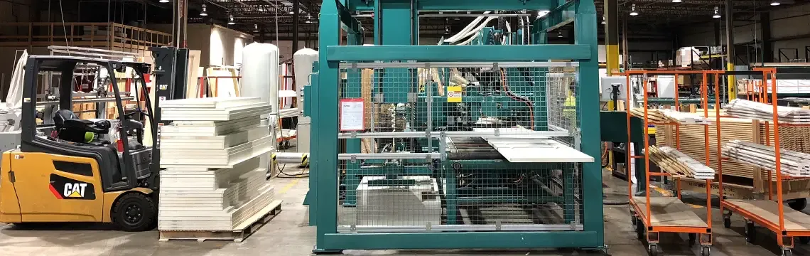 Door prehanging machine beside a forklift and stacked doors in a millwork hub