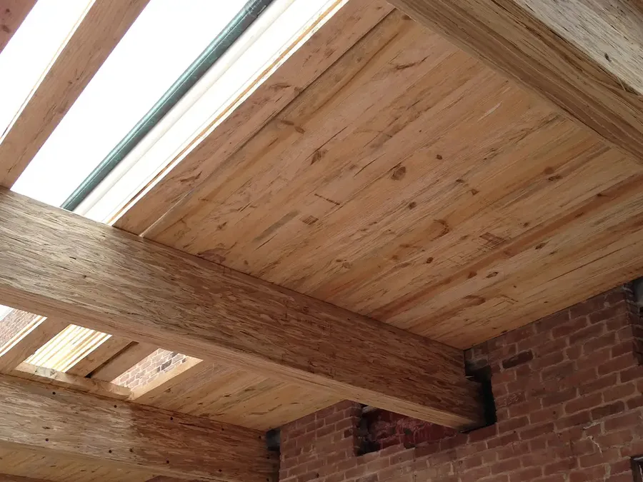 Laminated wood beams and plank ceiling decking set into an old brick wall