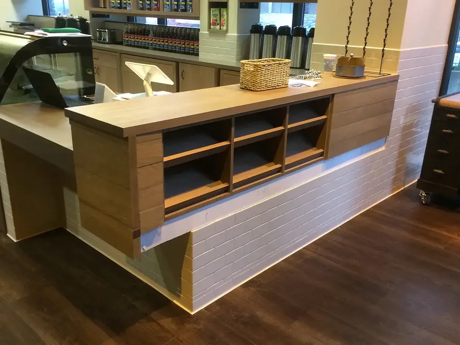 Coffee shop service counter with wood-look paneling and open cubby shelves