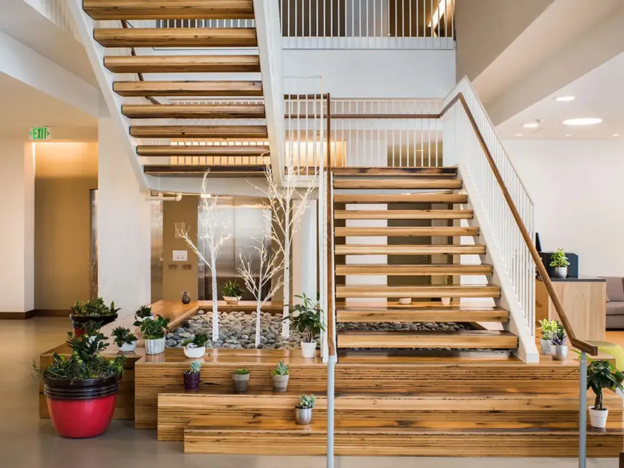 Open-tread wood staircase rising from tiered wood planters in a commercial lobby