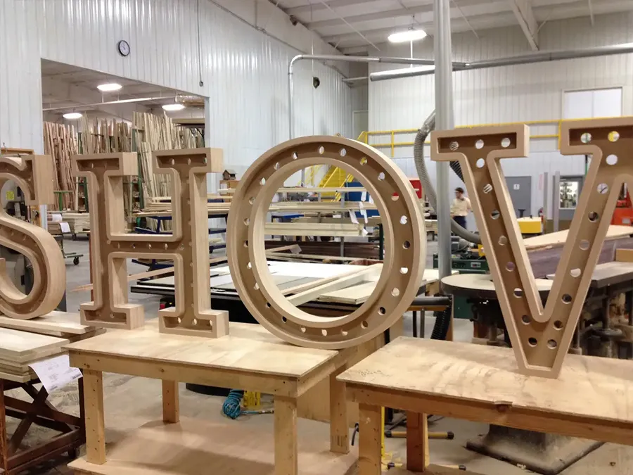 Large wood marquee letters with bulb holes being built in a millwork shop