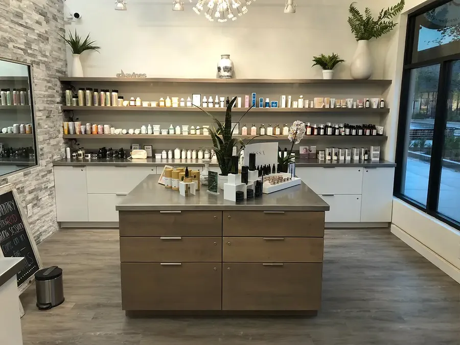 Retail showroom with a wood-drawer center island and wall shelves of beauty products