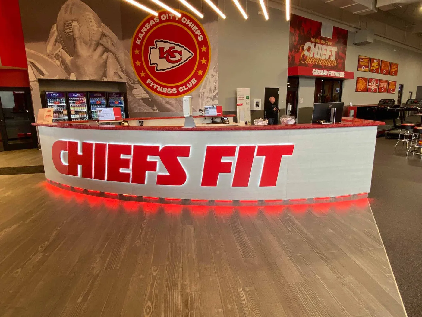 Curved fitness club reception desk with illuminated Chiefs Fit lettering