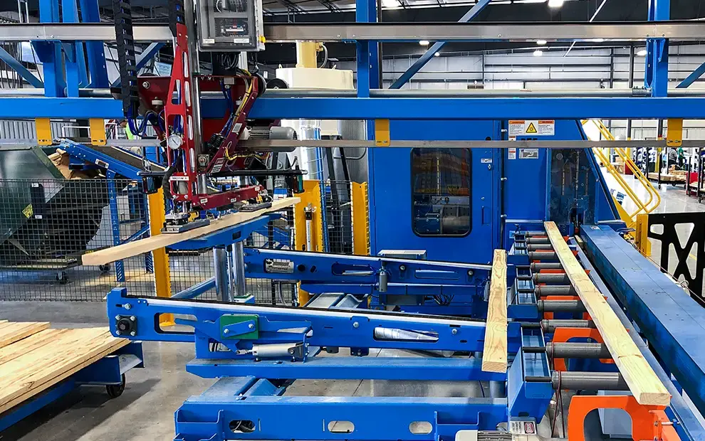 Automated saw line with robotic arm feeding boards onto blue conveyors