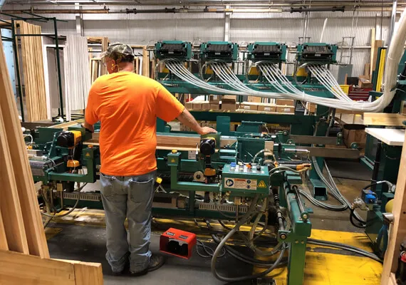 Worker operating a door frame assembly machine in a millwork shop