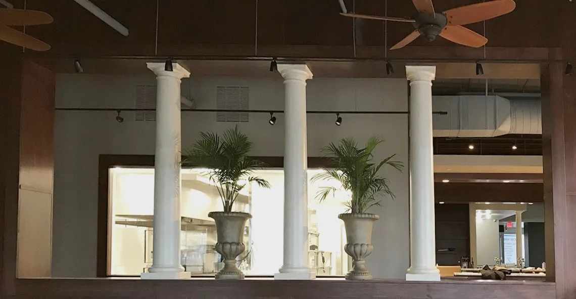 White columns with potted palms in urns framing a restaurant dining room