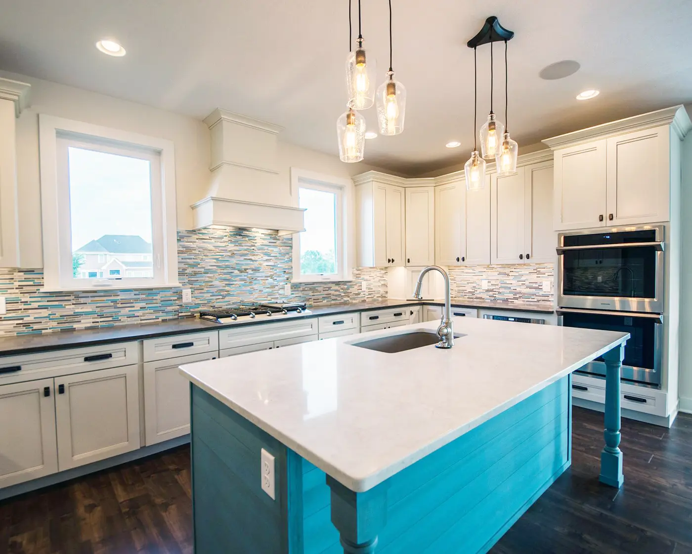 White kitchen with turquoise island, mosaic glass tile backsplash and glass pendants