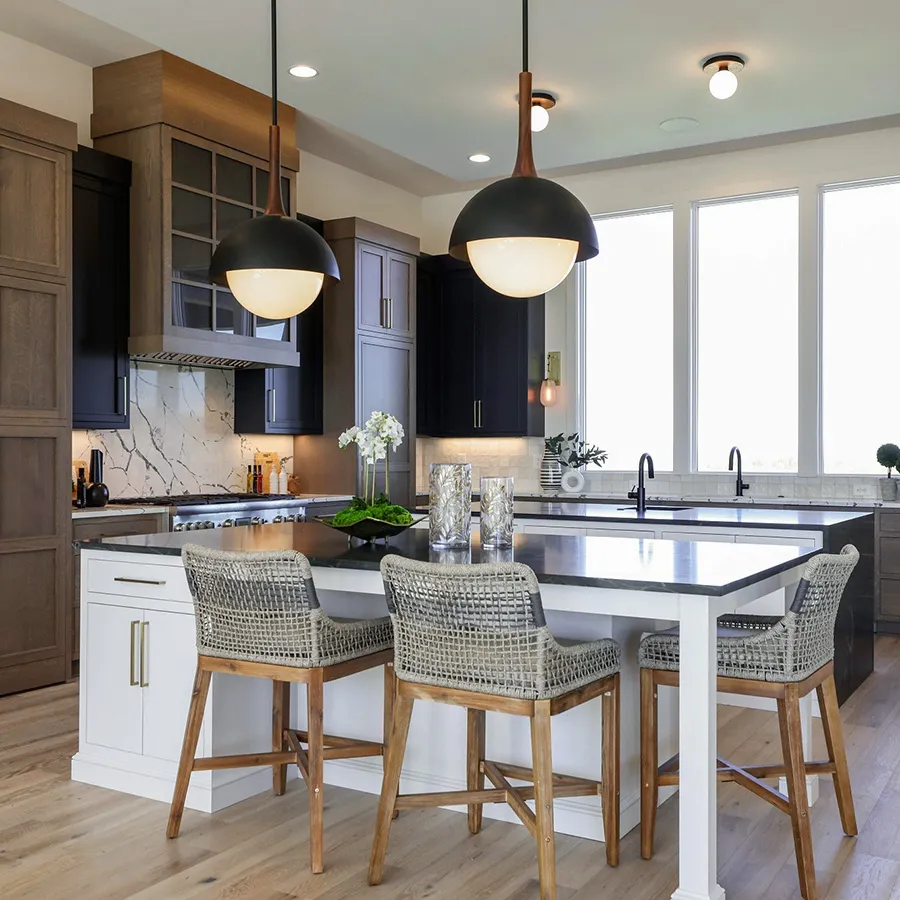 Kitchen with dark upper cabinets, white island, black countertops and woven bar stools